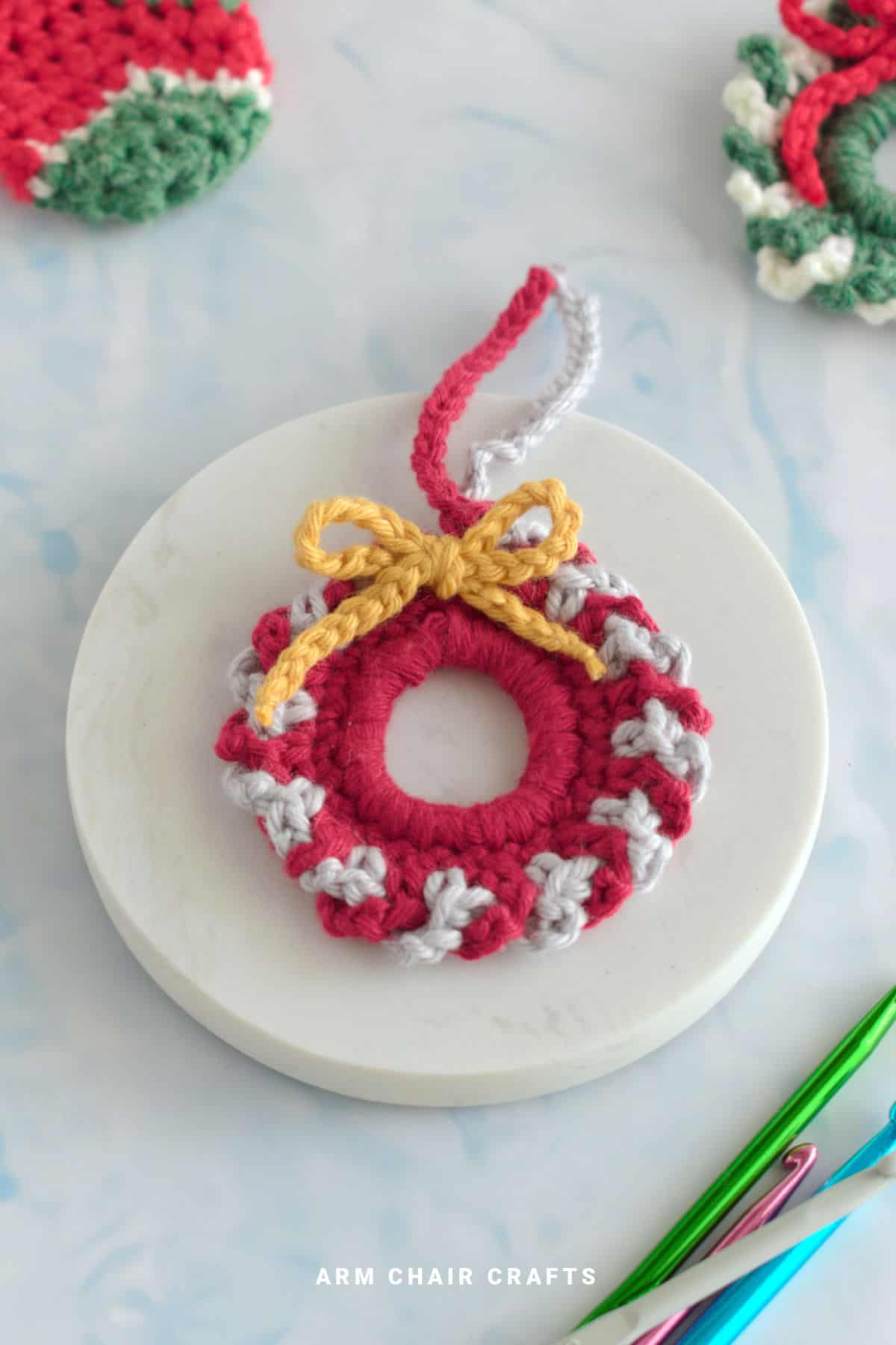 Red and grey mini crochet wreath with a yellow bow.