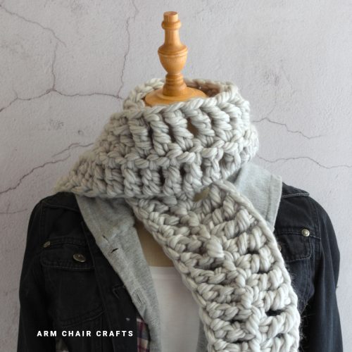 Close up image of a grey crochet scarf.