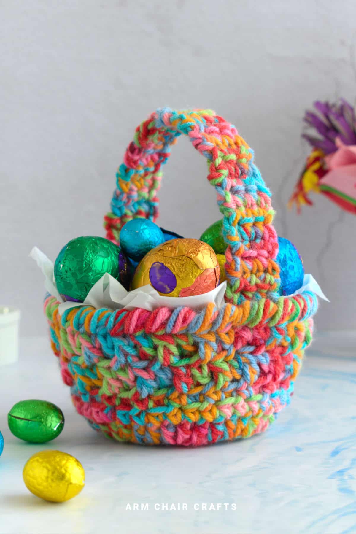 Crochet basket with handle filled with Easter eggs.