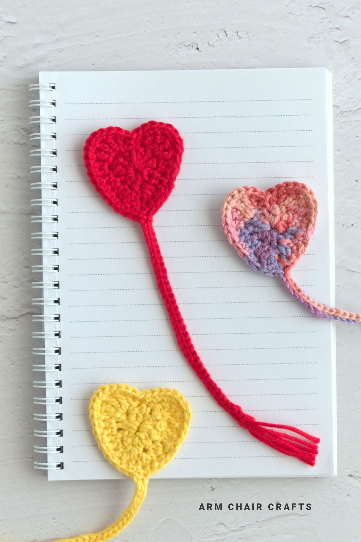Crochet heart bookmarks on a notebook.