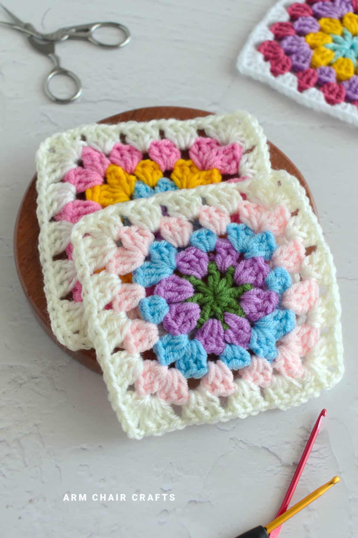 Crochet granny squares on a wooden board.