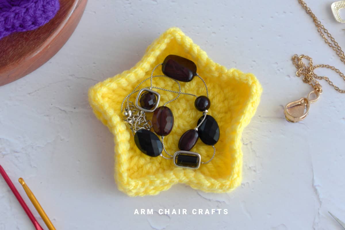Close up image of a yellow star crochet trinket box.