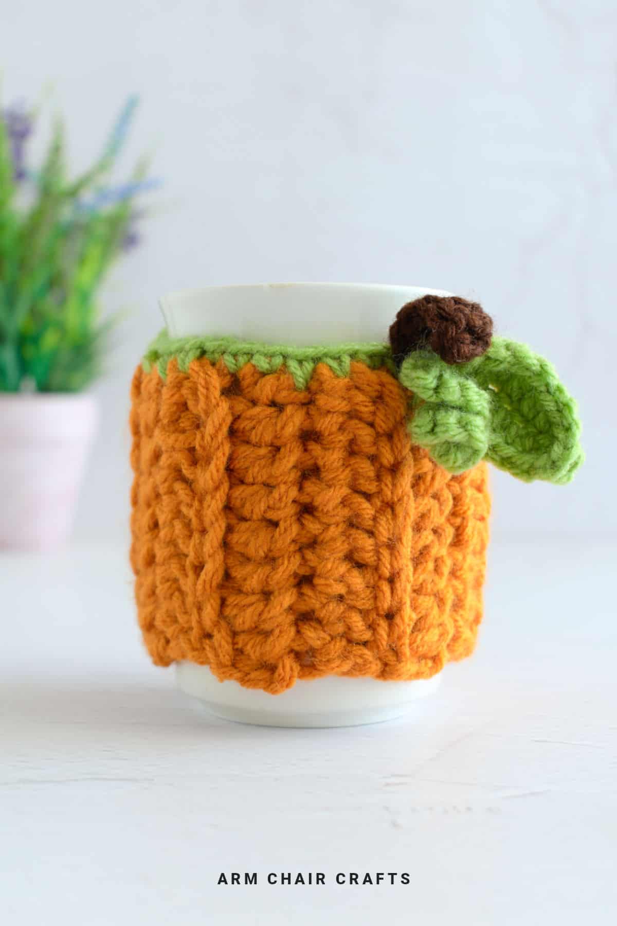 Crochet pumpkin mug cozy on a mug.