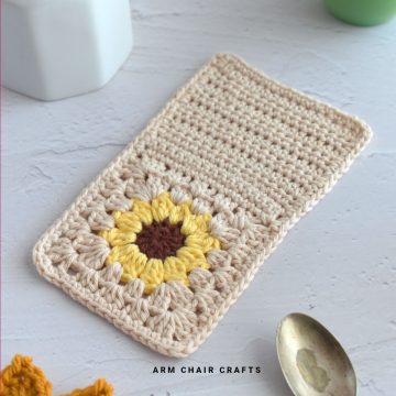 Close up image of a crochet sunflower mug rug.